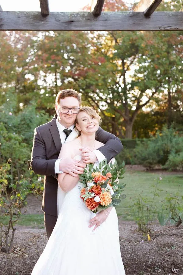 Bride and groom embracing and smiling in a garden