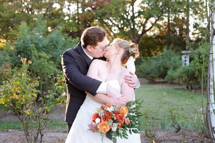 Bride and groom sharing a kiss in a garden at golden hour