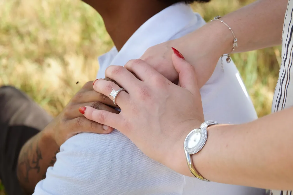 Close-up of couple holding hands, engagement ring on display