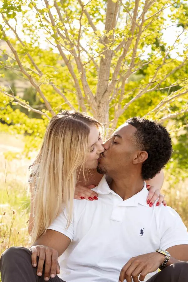 Couple kissing under a sunlit tree