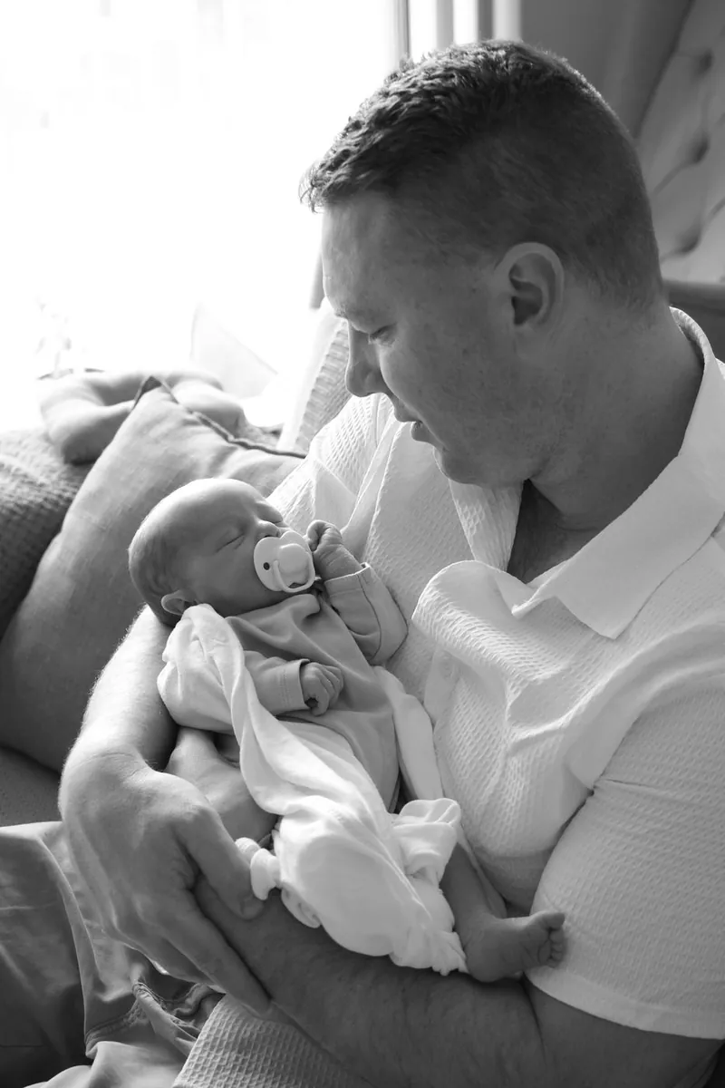 Father holding his sleeping newborn, black and white