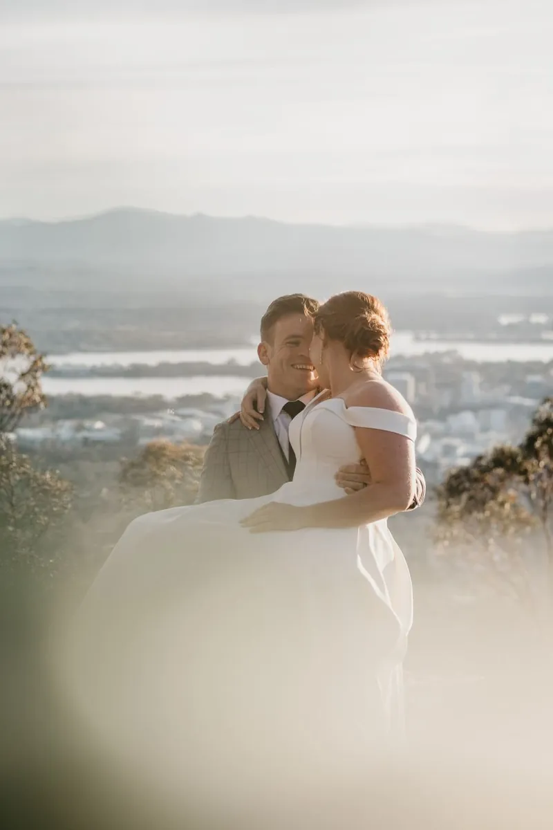 Groom carrying bride piggyback overlooking the city at golden hour