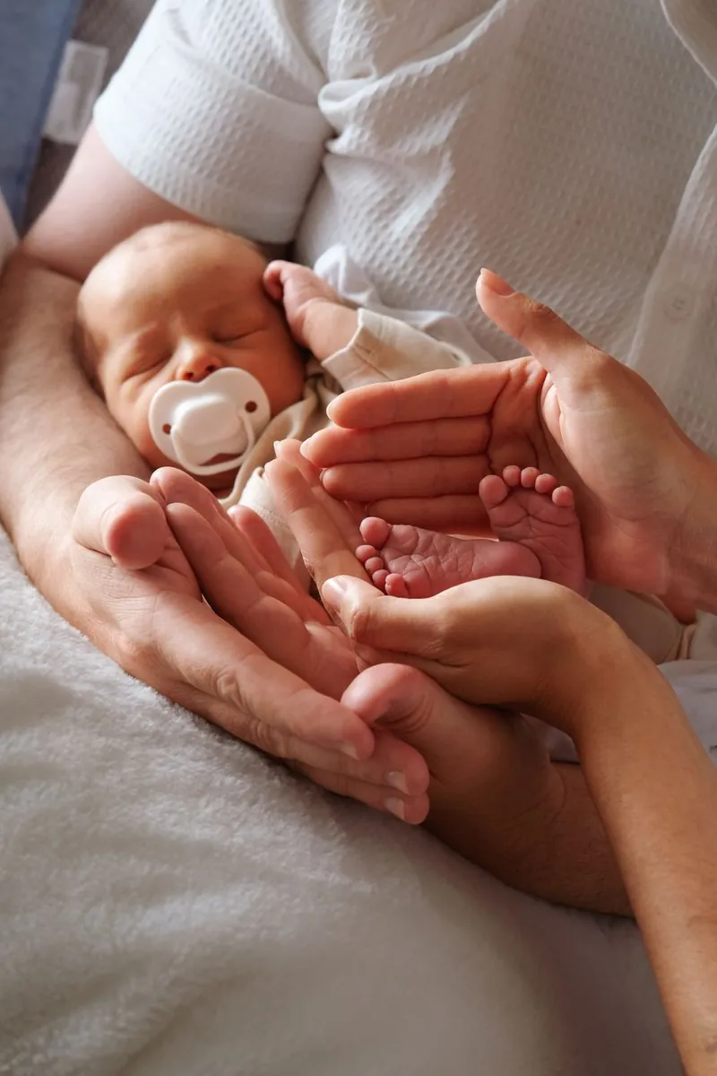 Parents' hands cradling their newborn's tiny feet