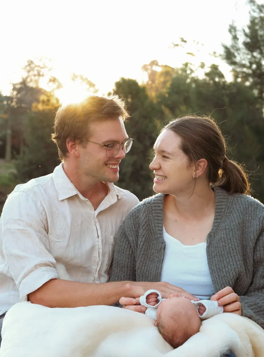 Parents smiling at each other while holding their newborn