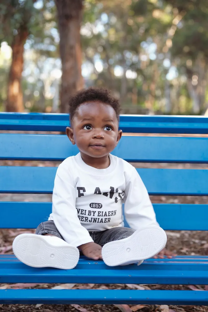 Toddler sitting on a blue park bench
